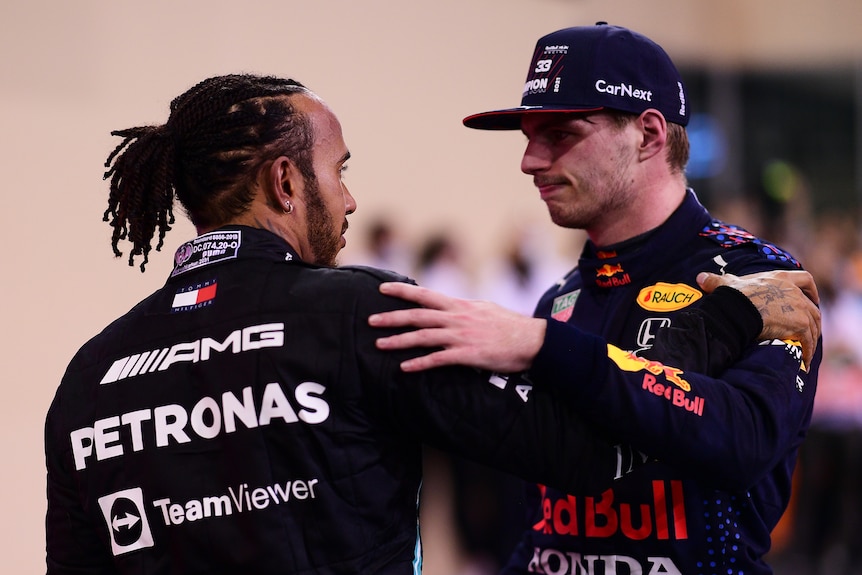 Two F1 drivers embrace after a race, holding each others arms and talking