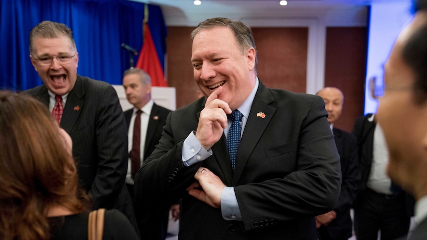 Pompeo holds hand to mouth while laughing, in the background Kritenbrink also laughs