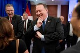 Pompeo holds hand to mouth while laughing, in the background Kritenbrink also laughs