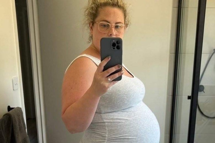 Rebecca takes a selfie with a pregnant belly