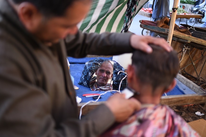 The face of a man reflected in a small mirror. 