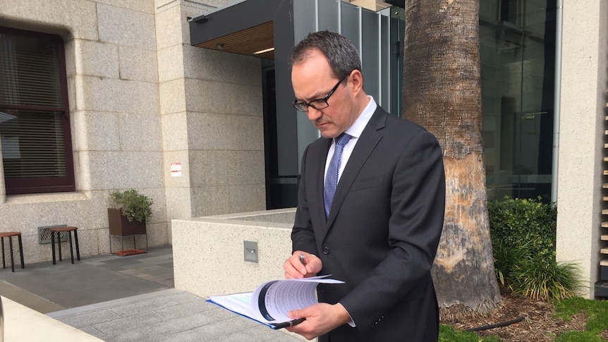 Liberal MP Corey Wingard looks down at paperwork.