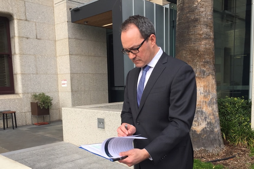 Liberal MP Corey Wingard looks down at paperwork.