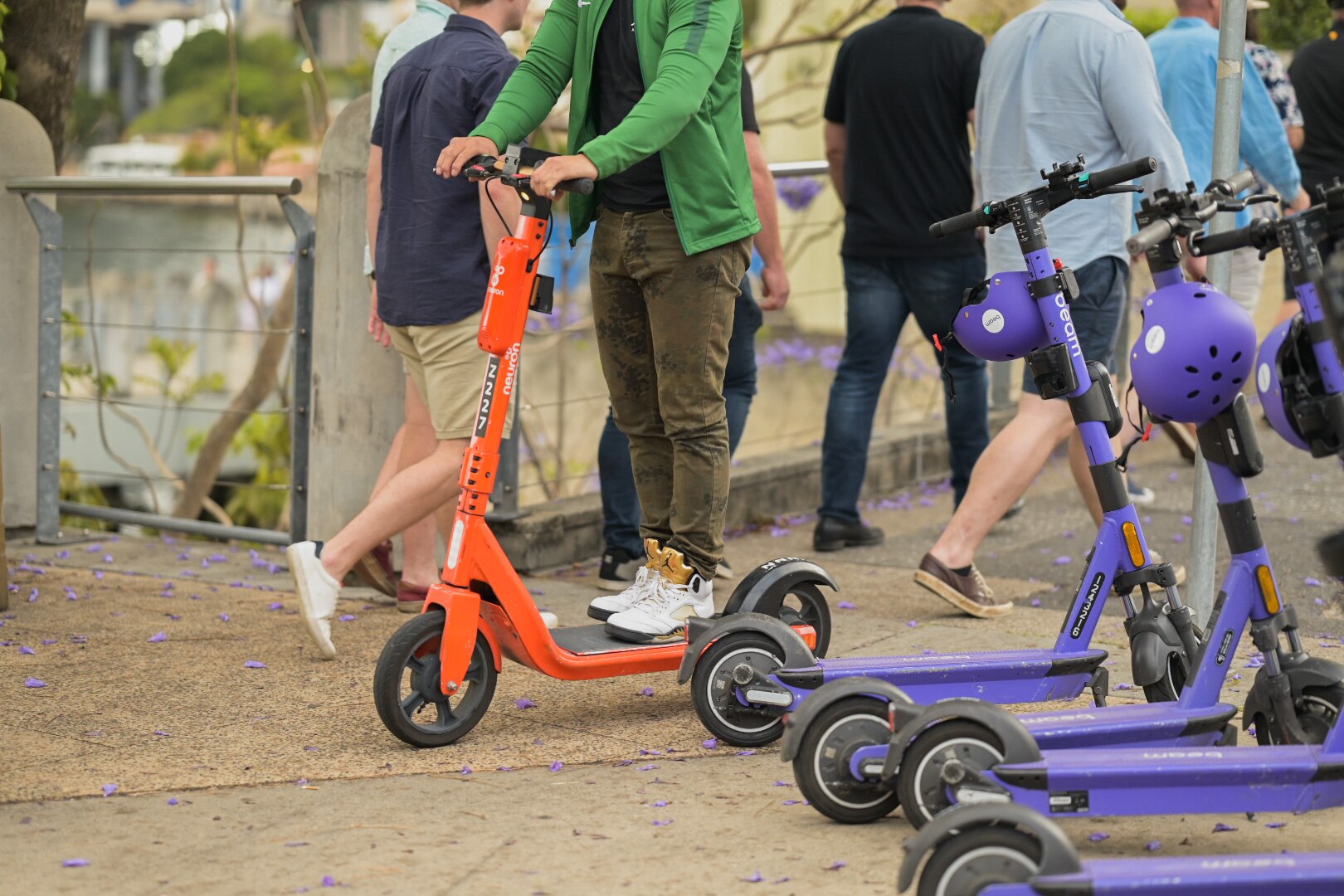 An unidentified person standing on an electric scooter with other scooters parked nearby.