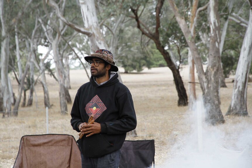 An Indigenous man among trees and a campsite in western Victoria