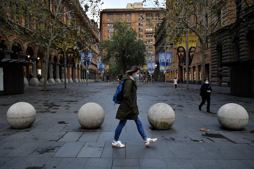 woman walks past empty street wearing a face mask