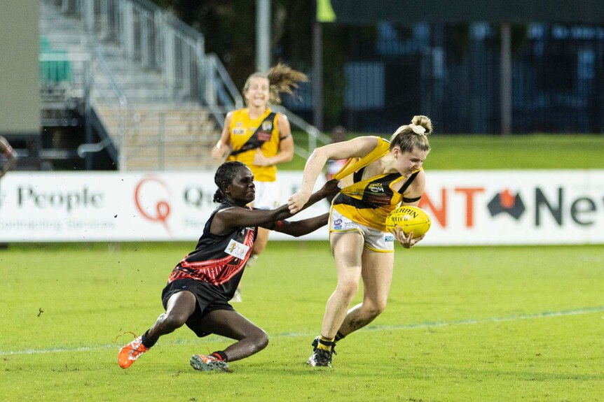 A Tiwi Bomber tackles a Nightcliff player on TIO Stadium.