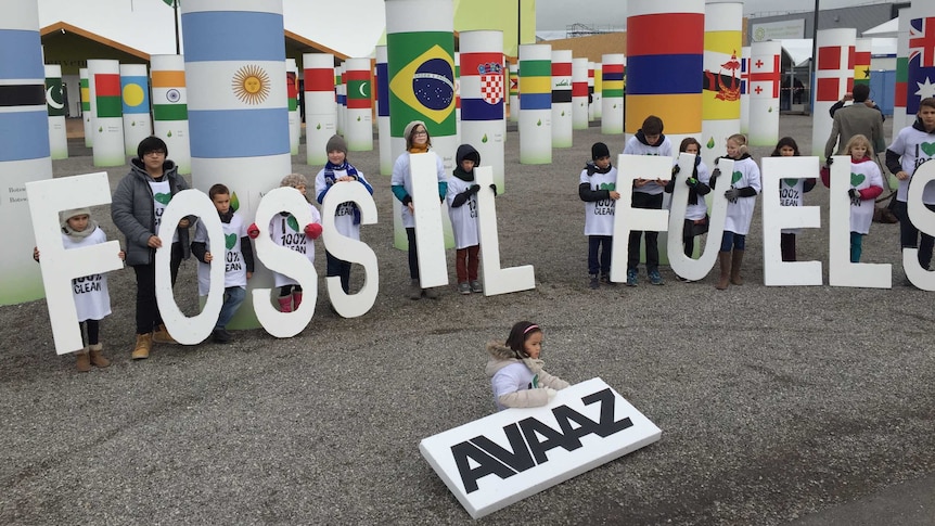 Children hold a sign saying 'Adieu fossil fuels' outside the Paris climate change conference on December 11, 2015