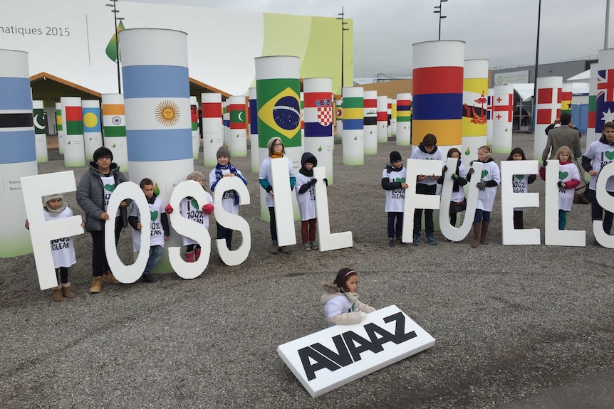 Children hold letters spelling 'adieu fossil fuels'