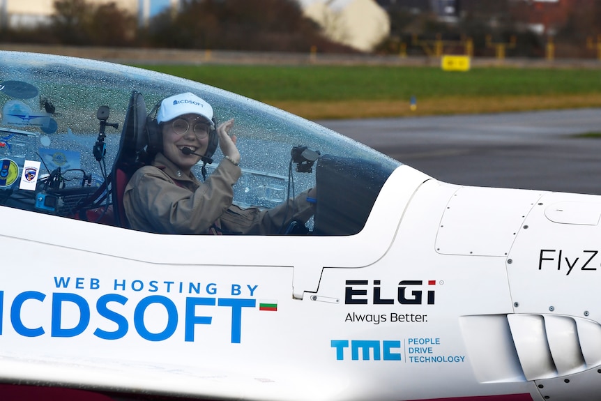 Woman sits in cockpit of plane smiling 