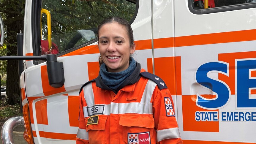 Jess Rice, wearing an orange SES uniform, in front of an SES truck.