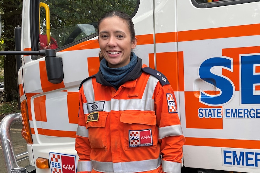 Jess Rice, wearing an orange SES uniform, in front of an SES truck.