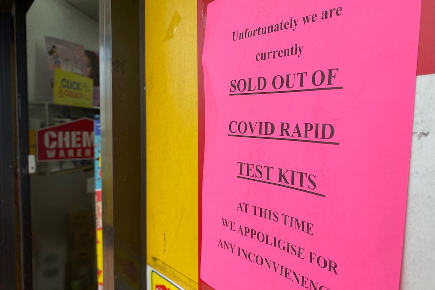 Un panneau rose avec un avertissement imprimé indiquant « vendu en rupture de stock de kits de test rapide COVID »