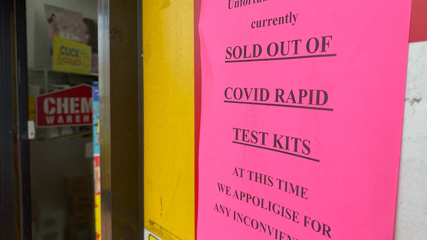 A pink sign with a printed warning that says 'sold out of covid rapid test kits'