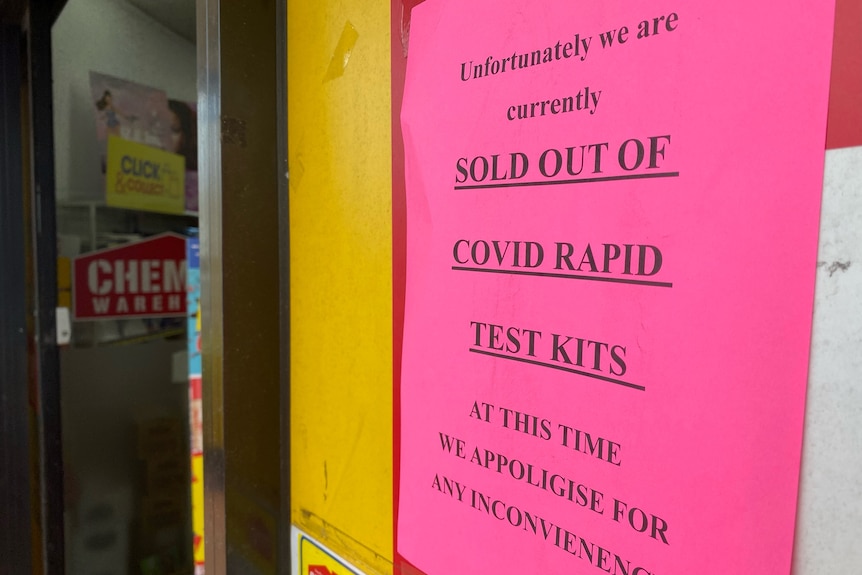 A pink sign with a printed warning that says 'sold out of COVID rapid test kits'