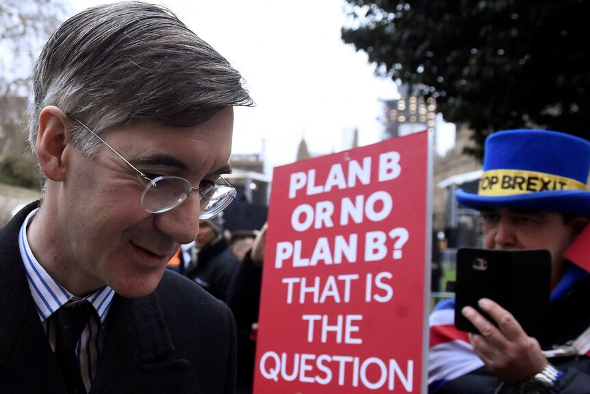 Conservative British MP Jacob Rees-Mogg walks past an anti-Brexit protester.