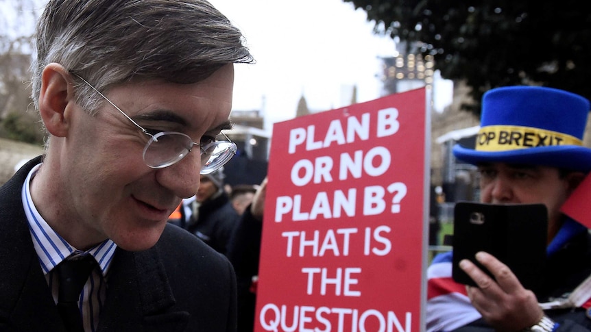 Conservative British MP Jacob Rees-Mogg walks past an anti-Brexit protester.