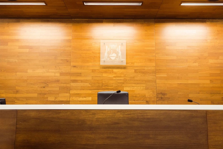 A judge's bench at the front of a courtroom with a single chair and a Supreme Court of WA logo on the wall.