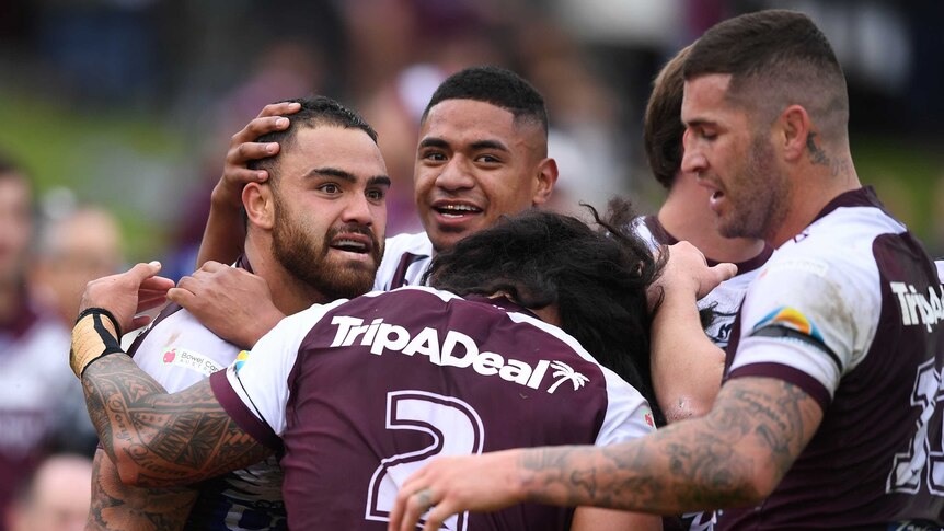 A group of NRL teammates hug and pat each other on the back after a try.