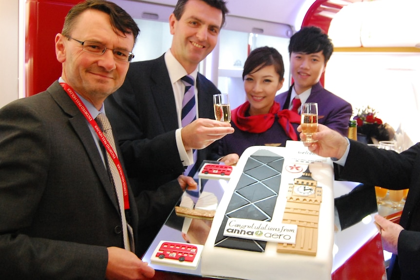 Four men and a woman with champagne and a large cake featuring London icons The Gherkin and Big Ben.