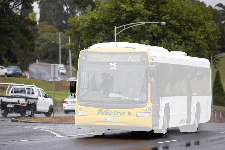A Metro bus highlighted in white drives down a street.
