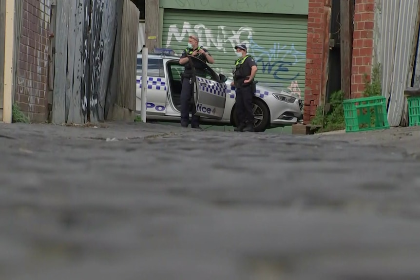 A police car and two officers at the end of a Melbourne laneway.