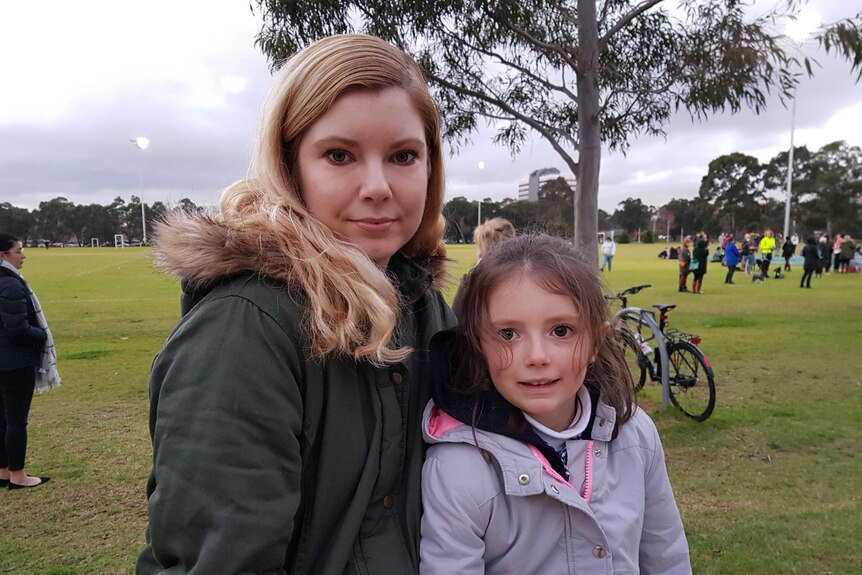Michal Proctor and her 6-year-old daughter Freya stand on the oval at Princes Park.