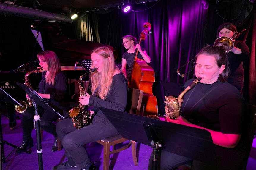 Female musicians perform on dimly lit stage