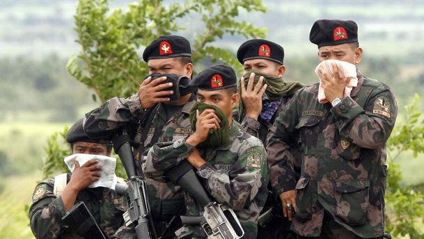 Filipino Police officers cover their noses while guarding the recovery of victims