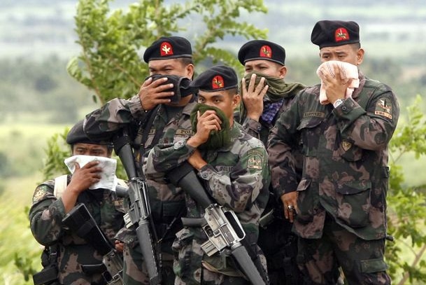 Filipino Police officers cover their noses while guarding the recovery of victims