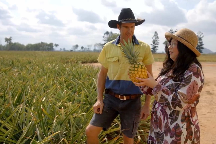 Two people looking at a pineapple