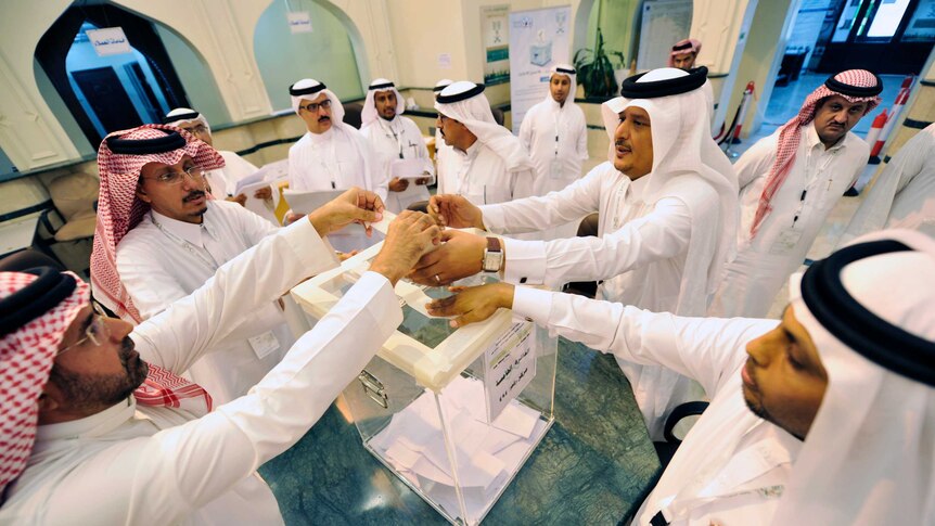 Saudi officials handle the ballot box.