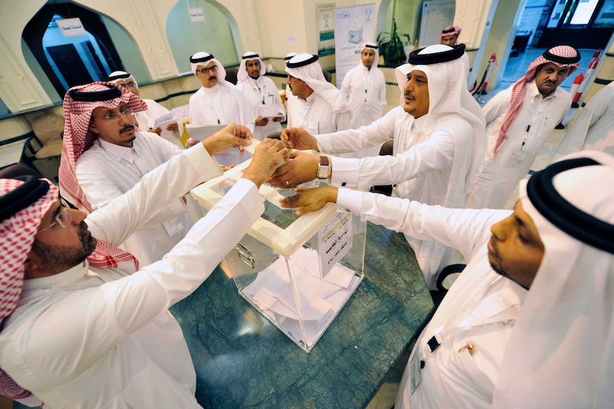 Saudi officials handle the ballot box.