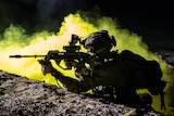 Silhouette of fully armed Australian soldier at night with smoke in backdrop
