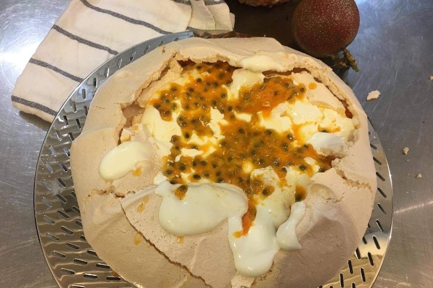 A pavlova covered with passionfruit.