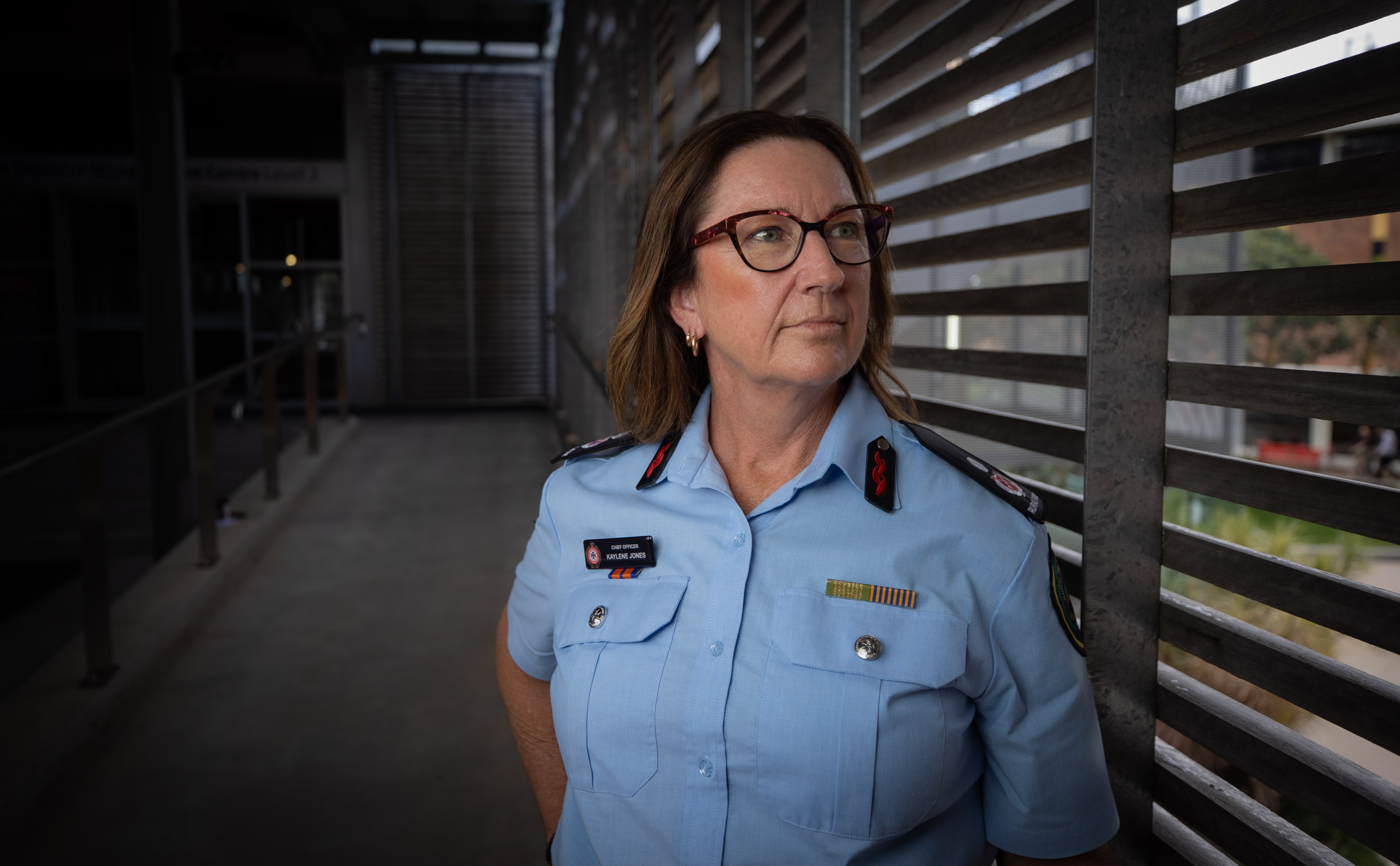 Una mujer con uniforme azul se apoya en una barandilla.