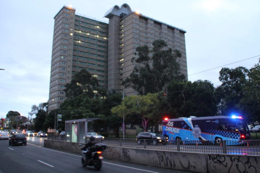 A police bus can be seen outside a public housing tower on Racecourse Road, Flemington, Melbourne.