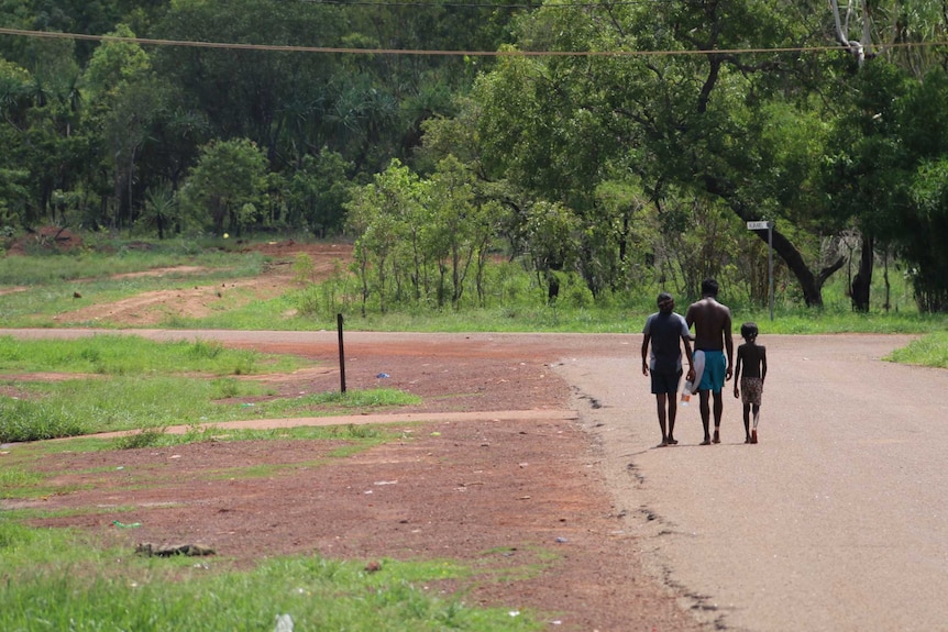 A group of  people walk down a street.