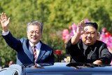 South Korean President Moon Jae-in and North Korean leader Kim Jong-un wave from the sunroof of a car.