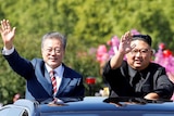 South Korean President Moon Jae-in and North Korean leader Kim Jong Un wave from the sunroof of a car.