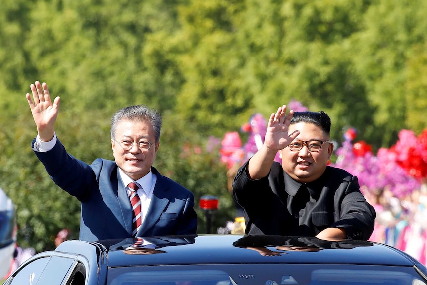 South Korean President Moon Jae-in and North Korean leader Kim Jong-un wave from the sunroof of a car.