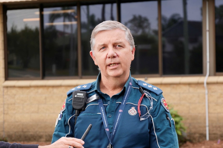 Neil Stead speaks in front of microphones.