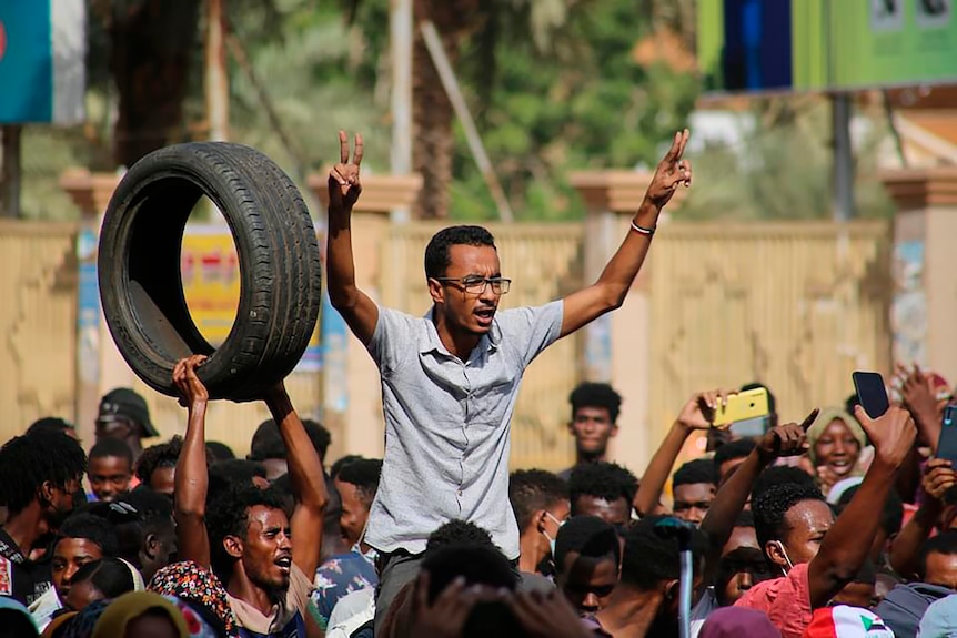 Man on shoulders in crowd with tyre.