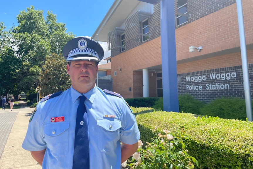 A policeman standing in front of the Wagga Wagga Police Station with his hands behind his back.