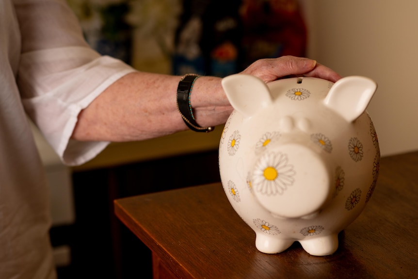 A woman's hand on a piggy bank.