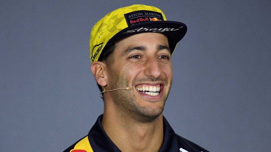 Daniel Ricciardo smiles while wearing a Red Bull hat.