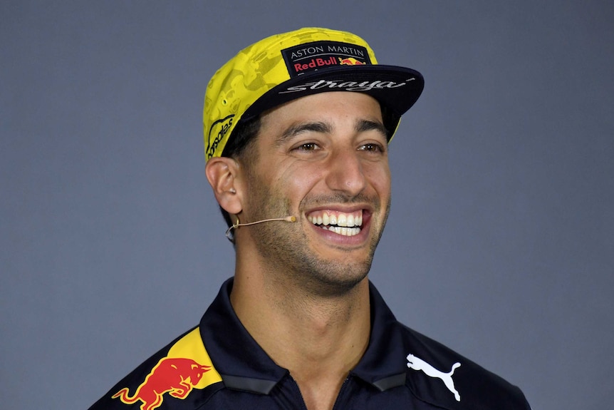 Daniel Ricciardo smiles while wearing a Red Bull hat.