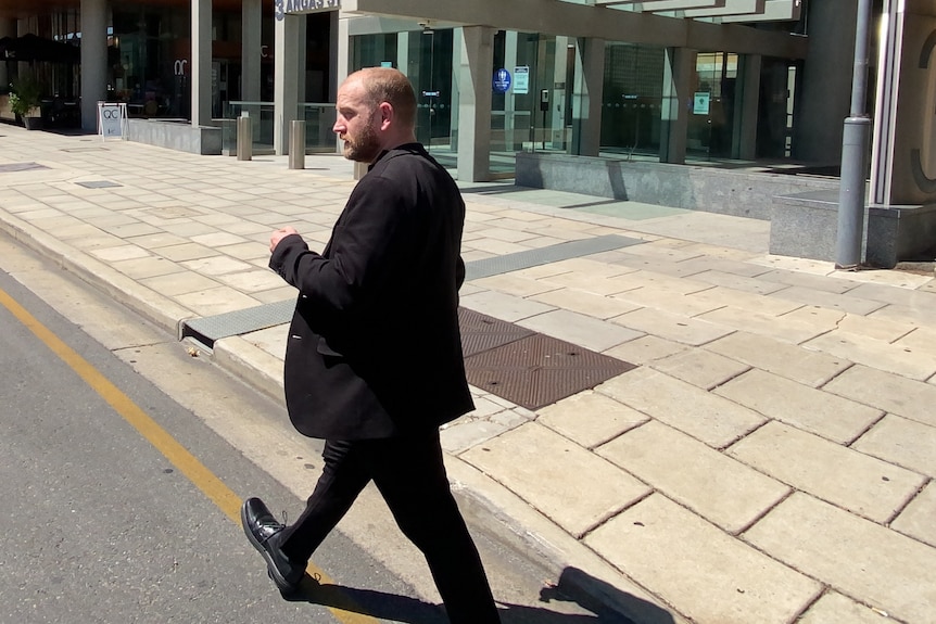 a man wearing a black suit walks away from the camera