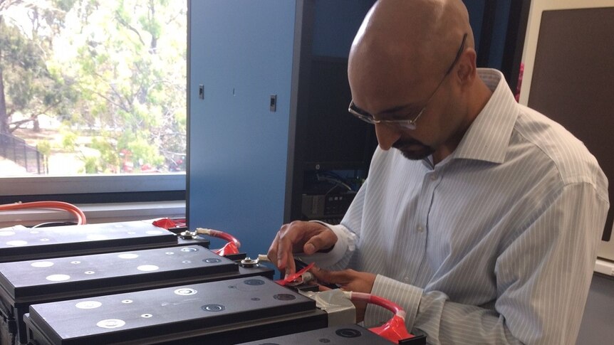 Dr Anand Bhatt from the CSIRO connecting batteries on a table with a cable.