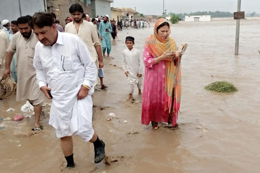 picture of a woman officer in Pakistan wearing long dress and walking through flood water